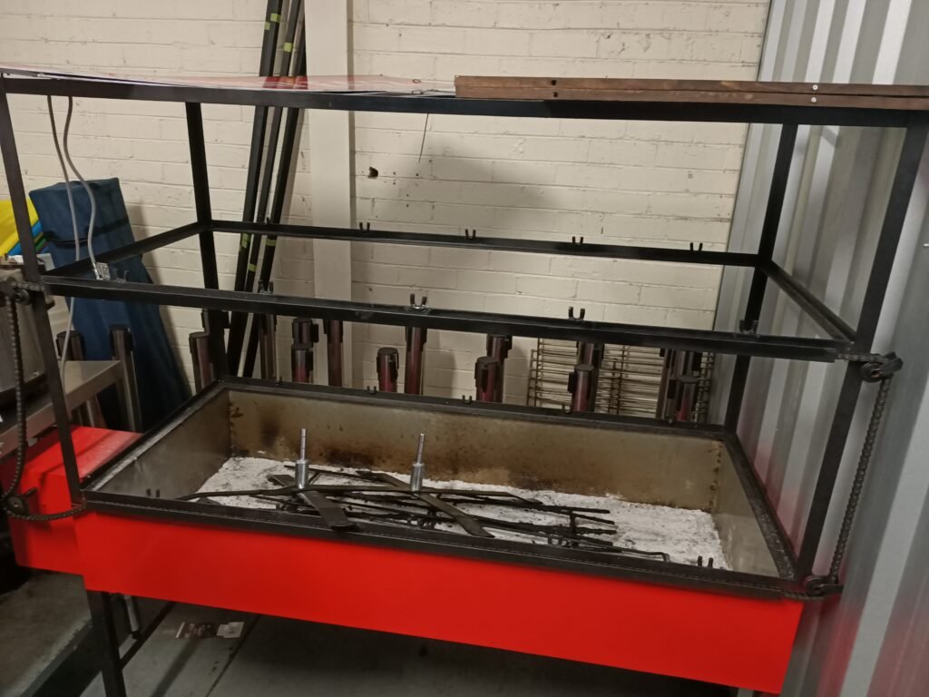 Custom black metal skewer barbecue frame over a red charcoal tray