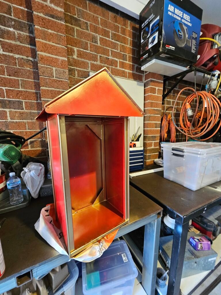 Custom Hanuman mandir with a pitched roof and red-and-gold finish in the workshop