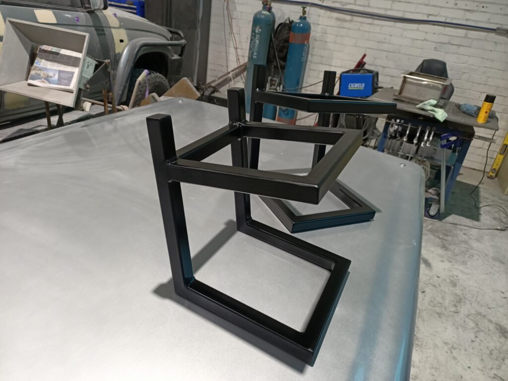 Matching black fabricated steel speaker stands on a workshop surface